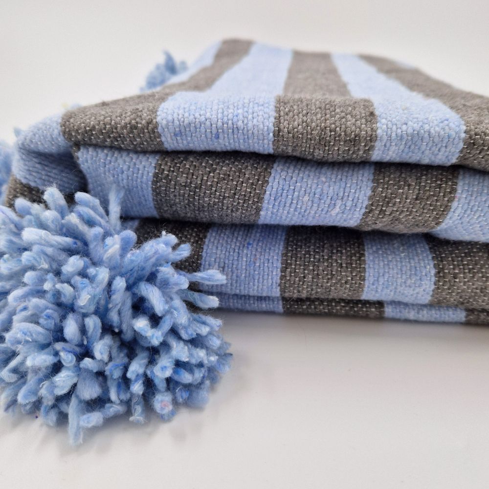 Handmade Moroccan pompom blanket with with blue and gray stripes and blue pompoms