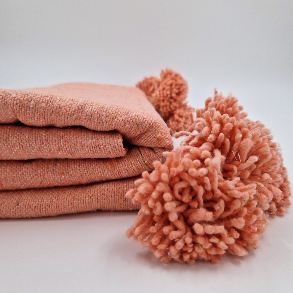 Handmade Moroccan pompom blanket in coral pink with golden lines