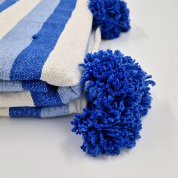 Handmade Moroccan Blanket with zebra stripes in blue pastel colors and blue pom poms