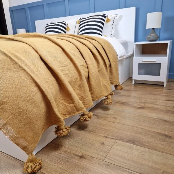 Nice modern design bedroom with blue wall paneling, mustard Moroccan pompom blanket, and zebra pompom pillows on the bed