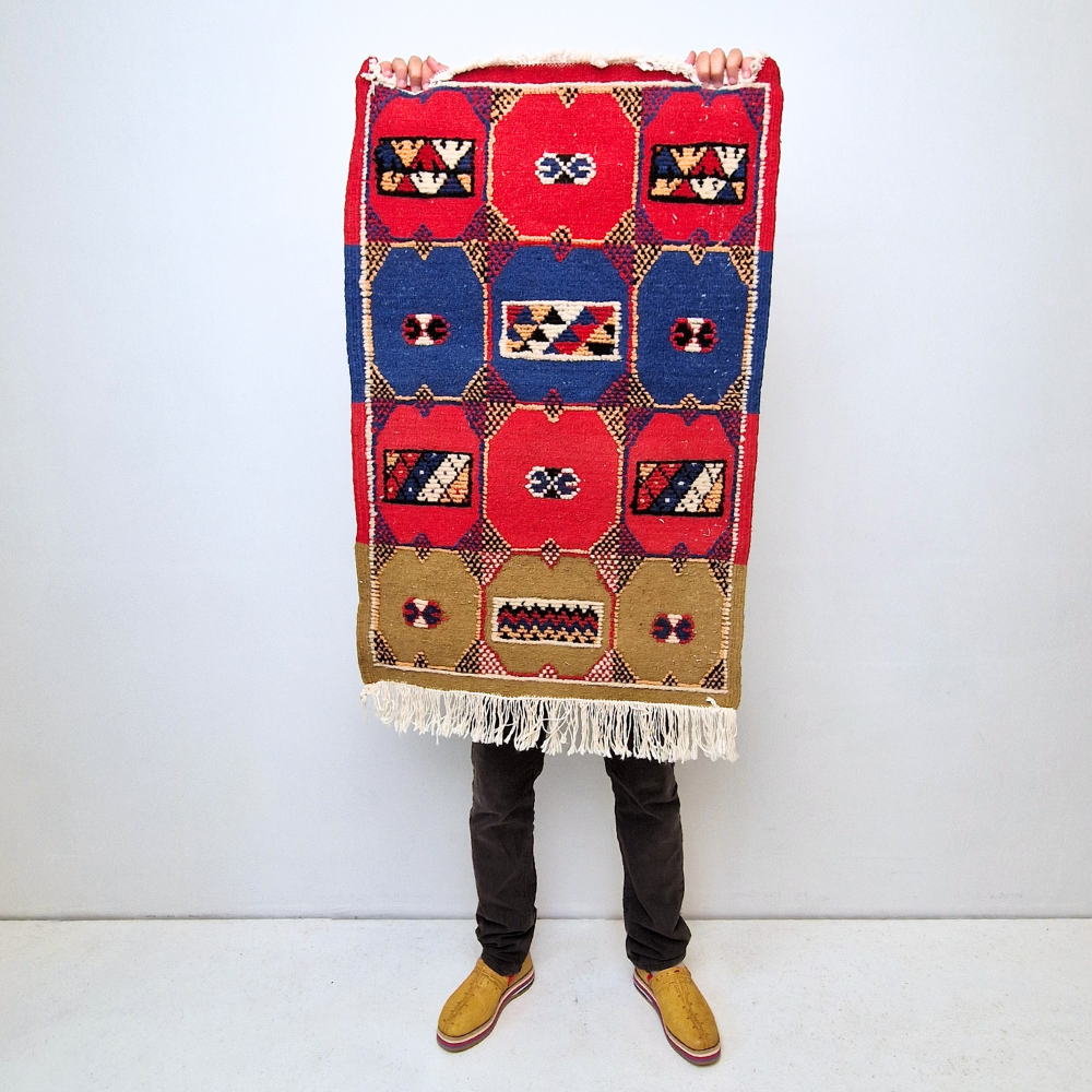 Bohemian Moroccan Azilal rug with bold geometric patterns in red, blue, white and multicolor wool, featuring abstract Berber tribal motifs and handwoven texture.