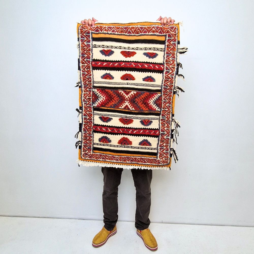 Bohemian Moroccan Azilal rug with bold geometric patterns in red, blue, white and multicolor wool, featuring abstract Berber tribal motifs and handwoven texture.