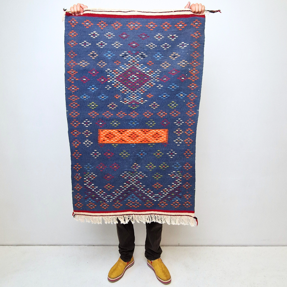 Bohemian Moroccan Azilal rug with bold geometric patterns in red, blue, white and multicolor wool, featuring abstract Berber tribal motifs and handwoven texture.