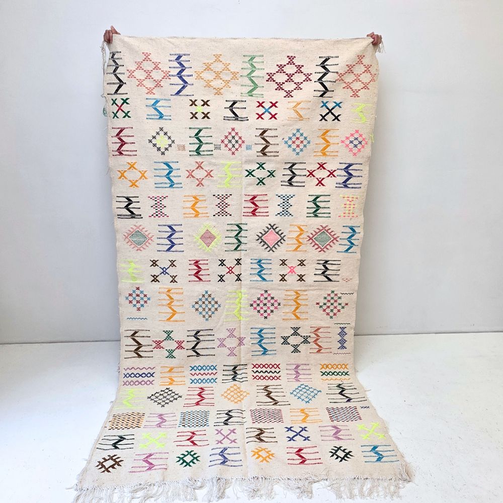 Colorful Moroccan Azilal rug with bold geometric patterns in red, orange, purple, and multicolor wool, featuring abstract Berber tribal motifs and handwoven texture.