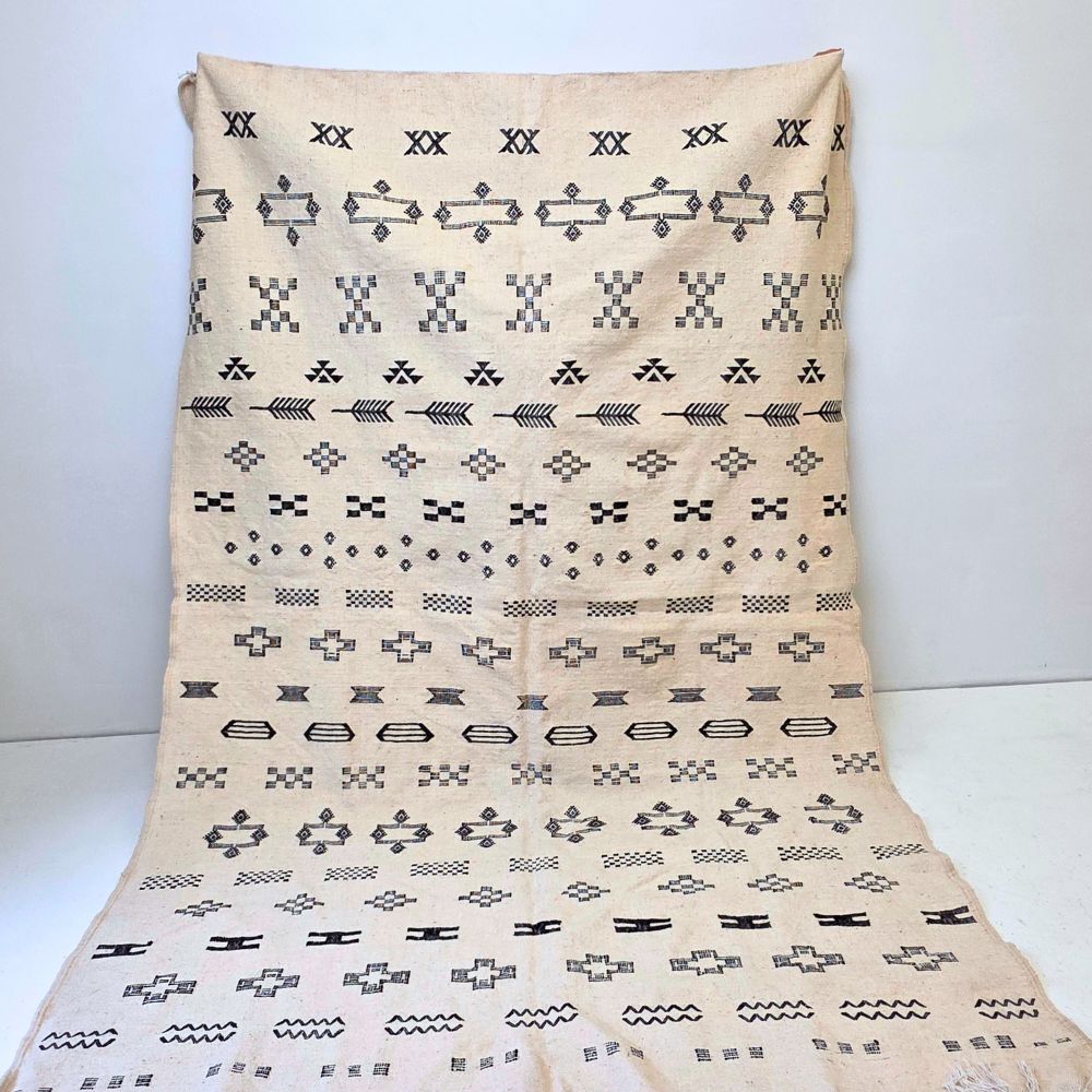 Minimalistic Moroccan Azilal rug with bold geometric patterns in white and black wool, featuring abstract Berber tribal motifs and handwoven texture.