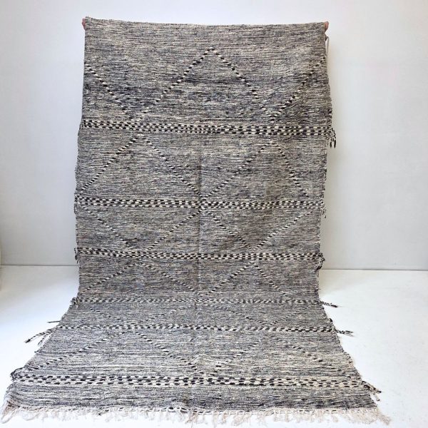 Minimalistic Moroccan Azilal rug with bold geometric patterns in white and black wool, featuring abstract Berber tribal motifs and handwoven texture.