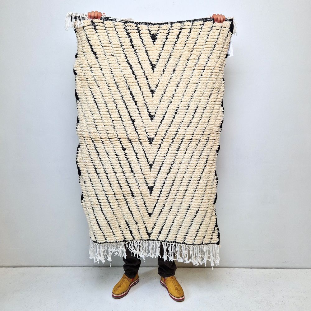 Minimalistic Moroccan Azilal rug with bold geometric patterns in white and black wool, featuring abstract Berber tribal motifs and handwoven texture.