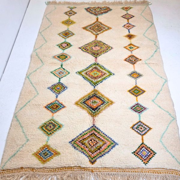 Colorful Moroccan Beni Ourain rug with blue, brown, red, black geometric patterns featuring abstract Berber tribal motifs and handwoven texture.