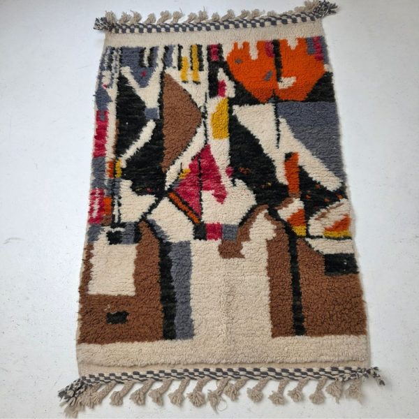 Colorful Moroccan Beni Ourain rug with blue, brown, red, black geometric patterns featuring abstract Berber tribal motifs and handwoven texture.