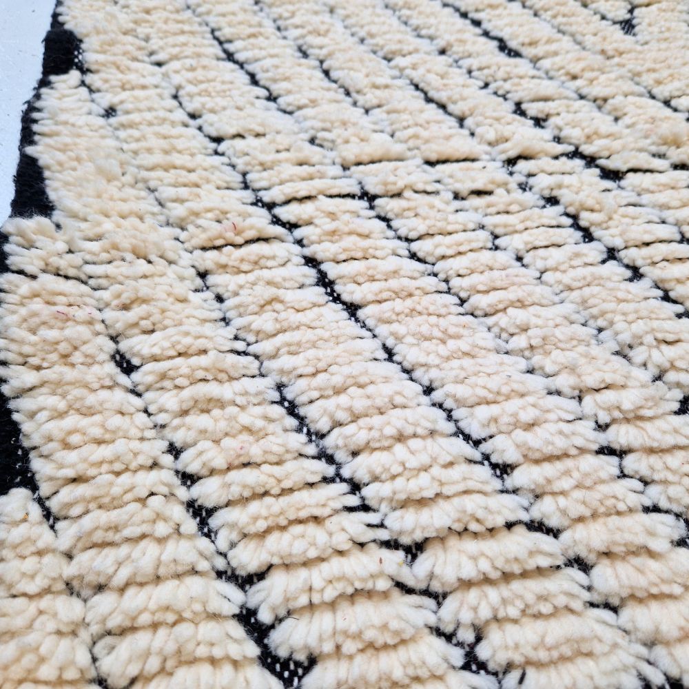 Minimalistic Moroccan Azilal rug with bold geometric patterns in white and black wool, featuring abstract Berber tribal motifs and handwoven texture.