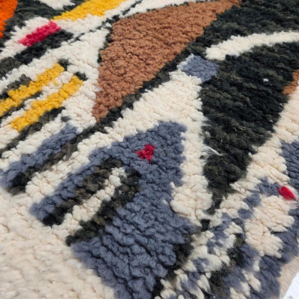 Colorful Moroccan Beni Ourain rug with blue, brown, red, black geometric patterns featuring abstract Berber tribal motifs and handwoven texture.