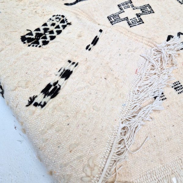 Minimalistic Moroccan Azilal rug with bold geometric patterns in white and black wool, featuring abstract Berber tribal motifs and handwoven texture.