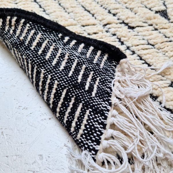 Minimalistic Moroccan Azilal rug with bold geometric patterns in white and black wool, featuring abstract Berber tribal motifs and handwoven texture.