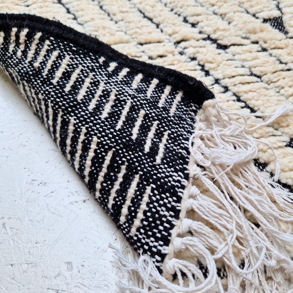 Minimalistic Moroccan Azilal rug with bold geometric patterns in white and black wool, featuring abstract Berber tribal motifs and handwoven texture.