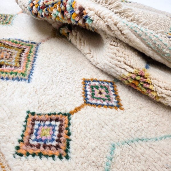 Colorful Moroccan Beni Ourain rug with blue, brown, red, black geometric patterns featuring abstract Berber tribal motifs and handwoven texture.