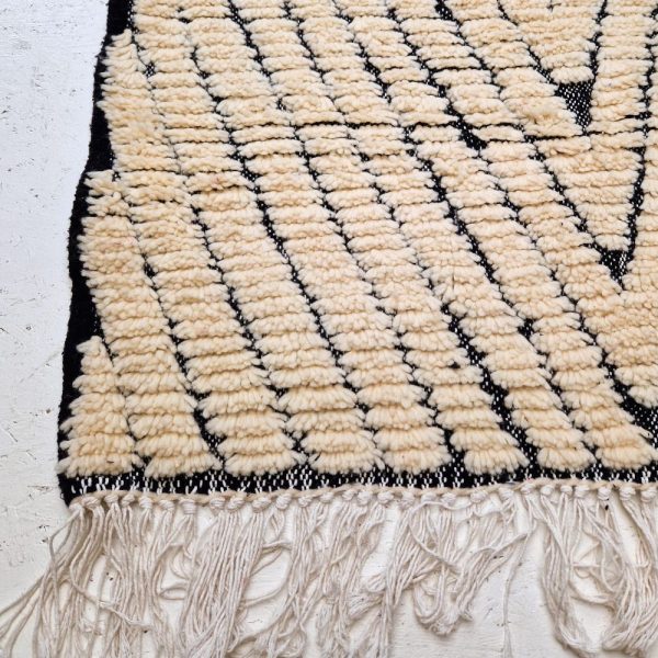 Minimalistic Moroccan Azilal rug with bold geometric patterns in white and black wool, featuring abstract Berber tribal motifs and handwoven texture.