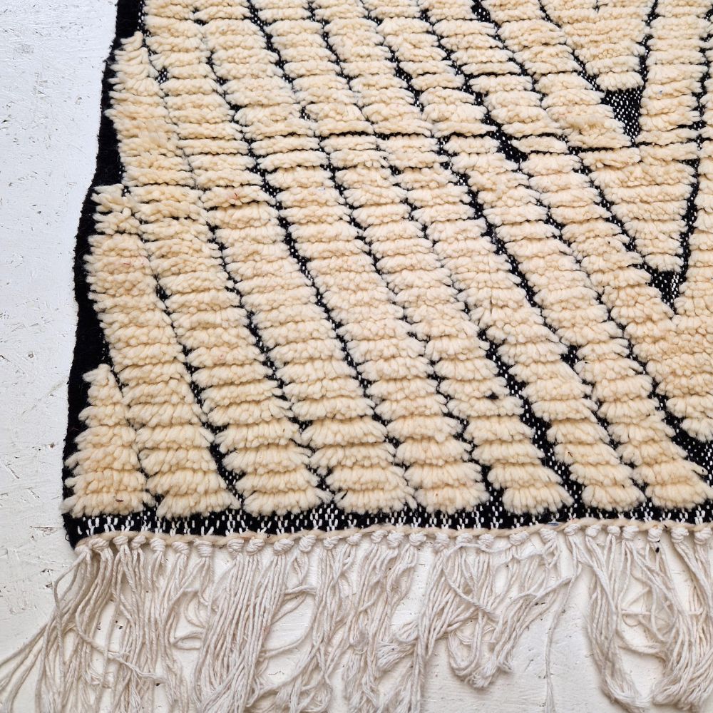 Minimalistic Moroccan Azilal rug with bold geometric patterns in white and black wool, featuring abstract Berber tribal motifs and handwoven texture.