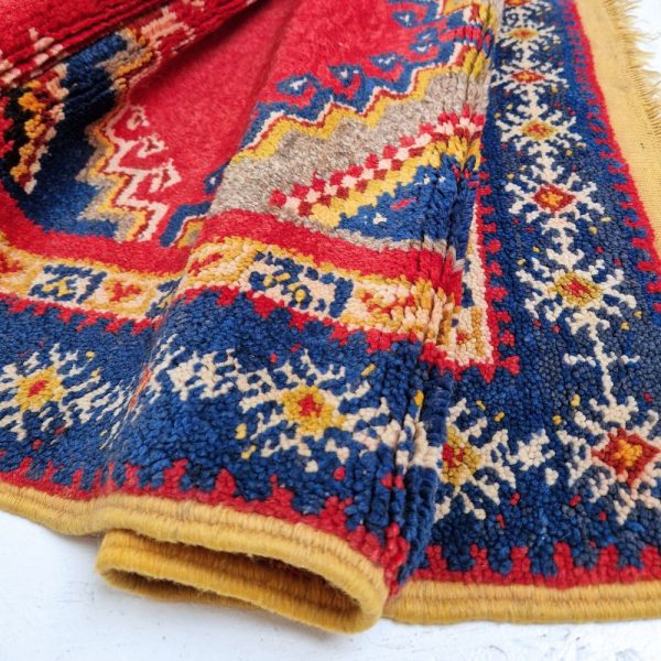 Colorful Moroccan Azilal rug with bold geometric patterns in red, orange, purple, and multicolor wool, featuring abstract Berber tribal motifs and handwoven texture.