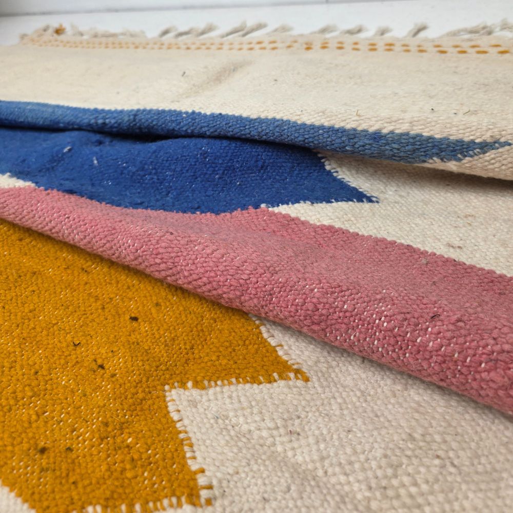 Colorful Moroccan rug with bold geometric patterns in orange, brown, purple, blue and multicolor wool, featuring abstract Berber tribal motifs and handwoven texture.