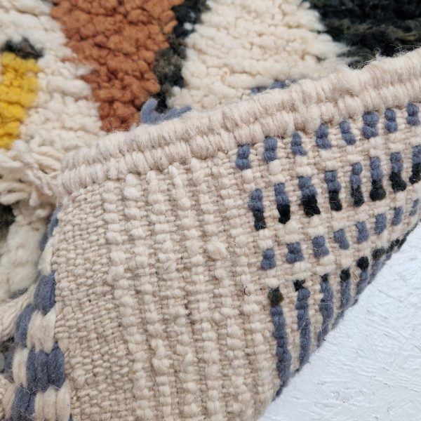 Colorful Moroccan Beni Ourain rug with blue, brown, red, black geometric patterns featuring abstract Berber tribal motifs and handwoven texture.