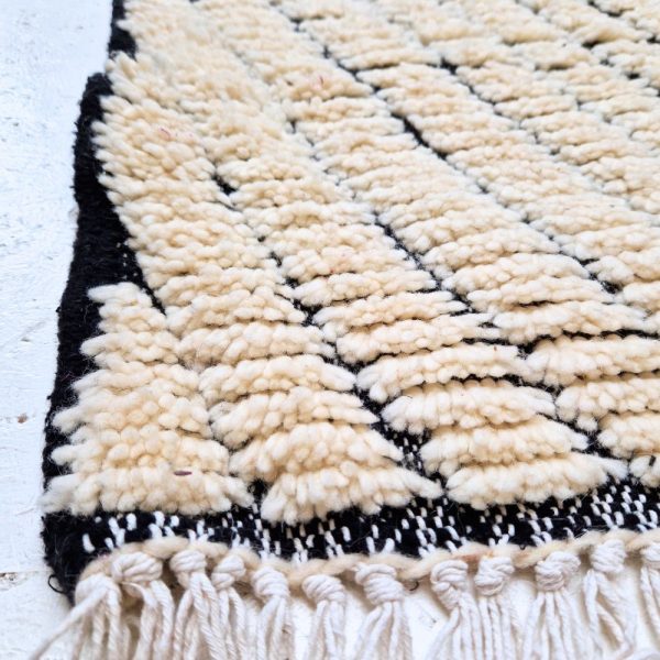 Minimalistic Moroccan Azilal rug with bold geometric patterns in white and black wool, featuring abstract Berber tribal motifs and handwoven texture.