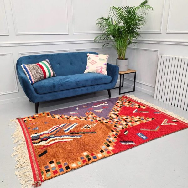 Colorful Moroccan Azilal rug with bold geometric patterns in red, orange, purple, and multicolor wool, featuring abstract Berber tribal motifs and handwoven texture.