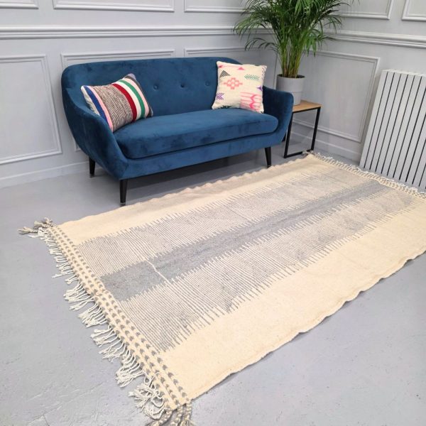 Minimalistic Moroccan Azilal rug with bold geometric patterns in white and blue wool, featuring abstract Berber tribal motifs and handwoven texture.