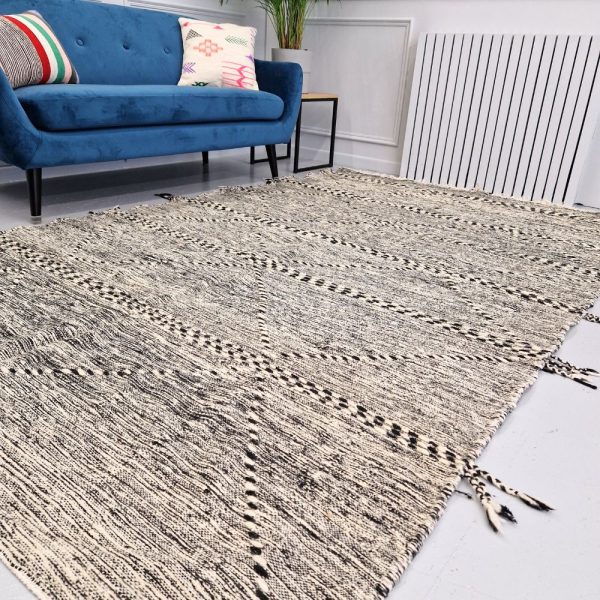 Minimalistic Moroccan Azilal rug with bold geometric patterns in white and black wool, featuring abstract Berber tribal motifs and handwoven texture.