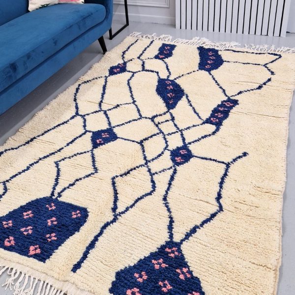 Colorful Moroccan Beni Ourain rug with blue and pink geometric patterns featuring abstract Berber tribal motifs and handwoven texture.
