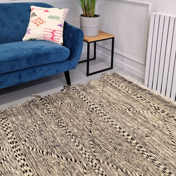 Minimalistic Moroccan Azilal rug with bold geometric patterns in white and black wool, featuring abstract Berber tribal motifs and handwoven texture.