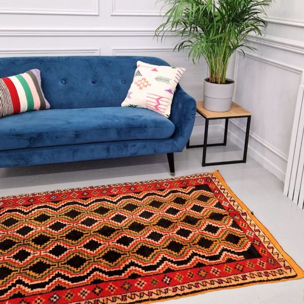 Colorful Moroccan Azilal rug with bold geometric patterns in red, orange, black and multicolor wool, featuring abstract Berber tribal motifs and handwoven texture.