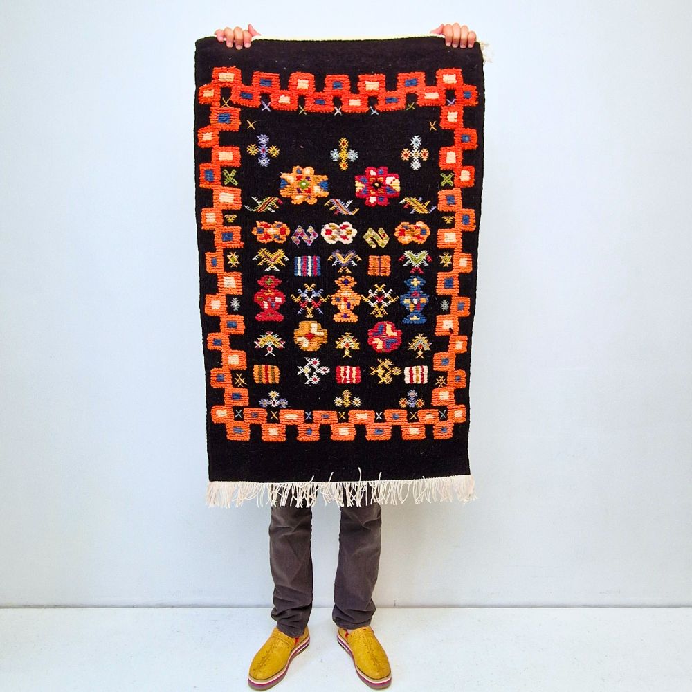 Colorful Taznakht Black Small Rug with bold geometric patterns in red, orange, purple, and multicolor wool, featuring abstract Berber tribal motifs and handwoven texture.