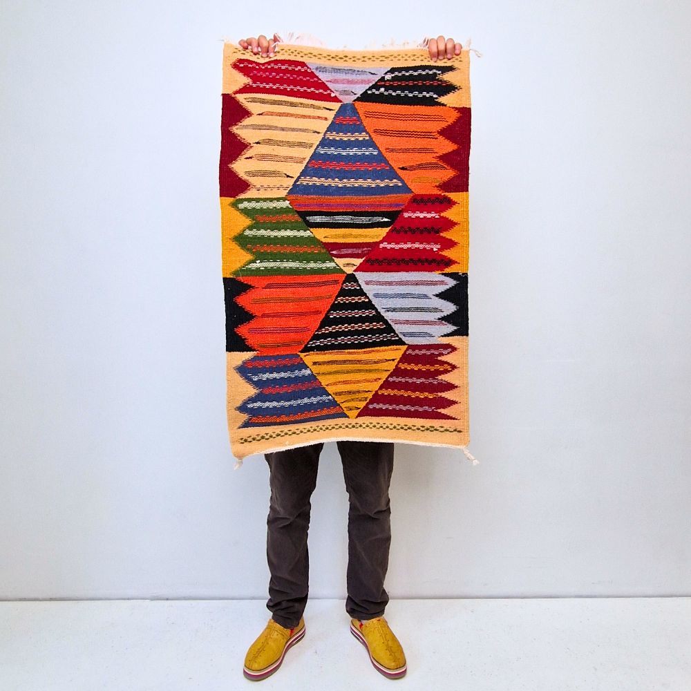 Colorful Moroccan Azilal rug with bold geometric patterns in red, orange, purple, and multicolor wool, featuring abstract Berber tribal motifs and handwoven texture.