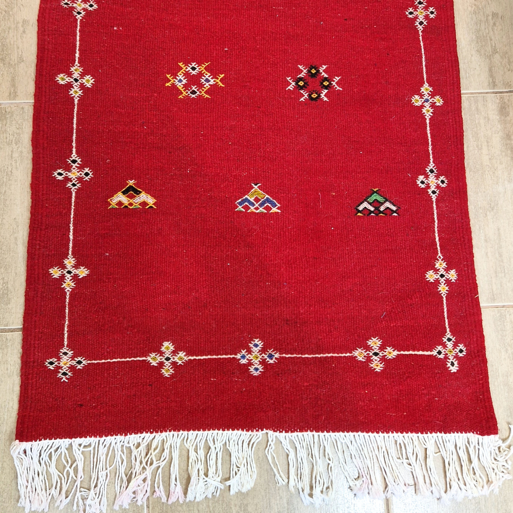 Bohemian Moroccan Azilal rug with bold geometric patterns in red, blue, white and multicolor wool, featuring abstract Berber tribal motifs and handwoven texture.