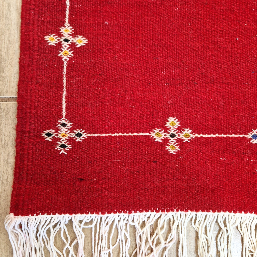 Bohemian Moroccan Azilal rug with bold geometric patterns in red, blue, white and multicolor wool, featuring abstract Berber tribal motifs and handwoven texture.