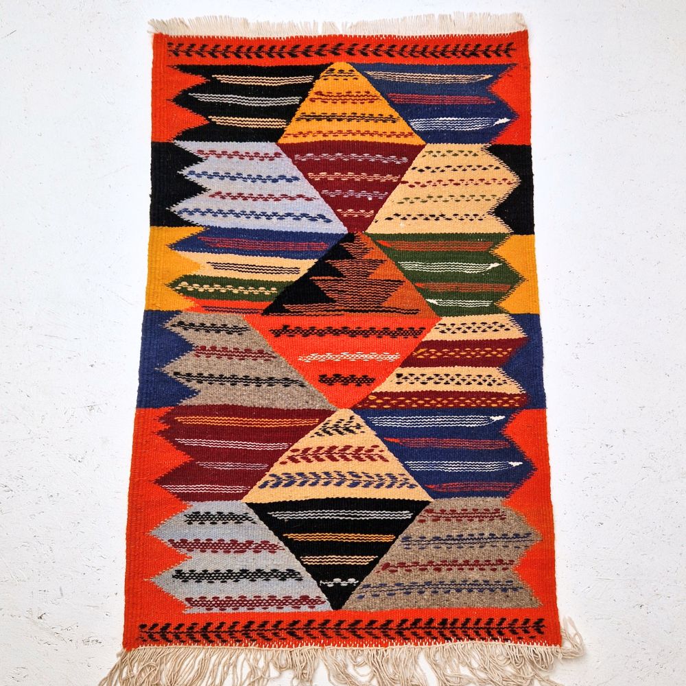 Colorful Moroccan Azilal rug with bold geometric patterns in red, orange, purple, and multicolor wool, featuring abstract Berber tribal motifs and handwoven texture.