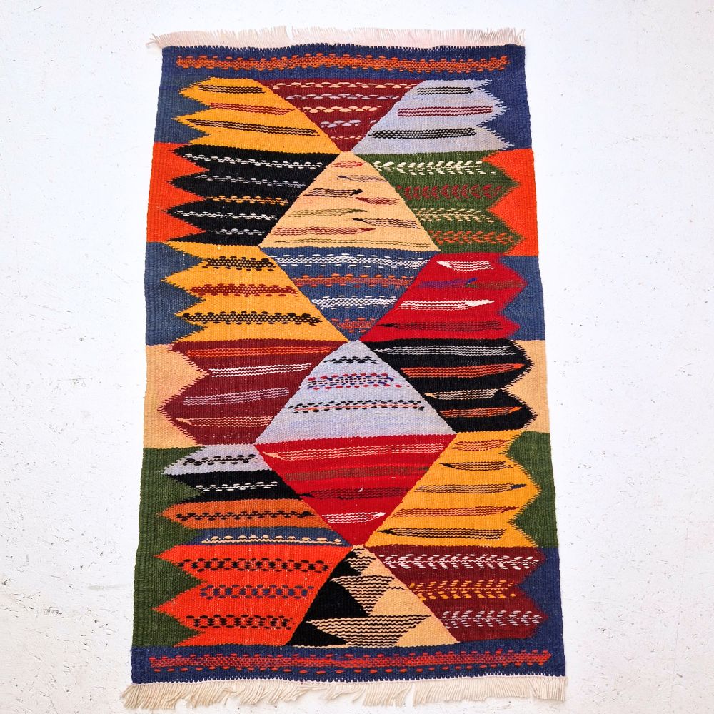 Colorful Moroccan Azilal rug with bold geometric patterns in red, orange, purple, and multicolor wool, featuring abstract Berber tribal motifs and handwoven texture.