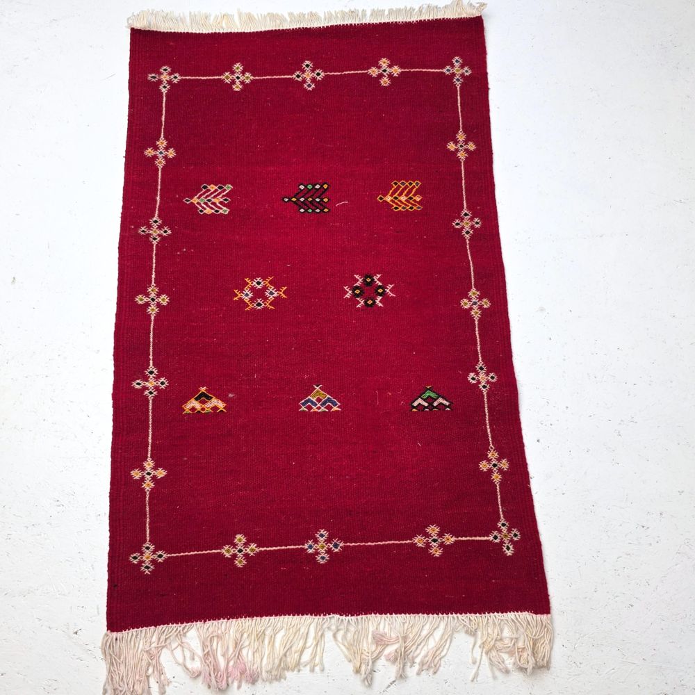 Bohemian Moroccan Azilal rug with bold geometric patterns in red, orange, purple, and multicolor wool, featuring abstract Berber tribal motifs and handwoven texture.