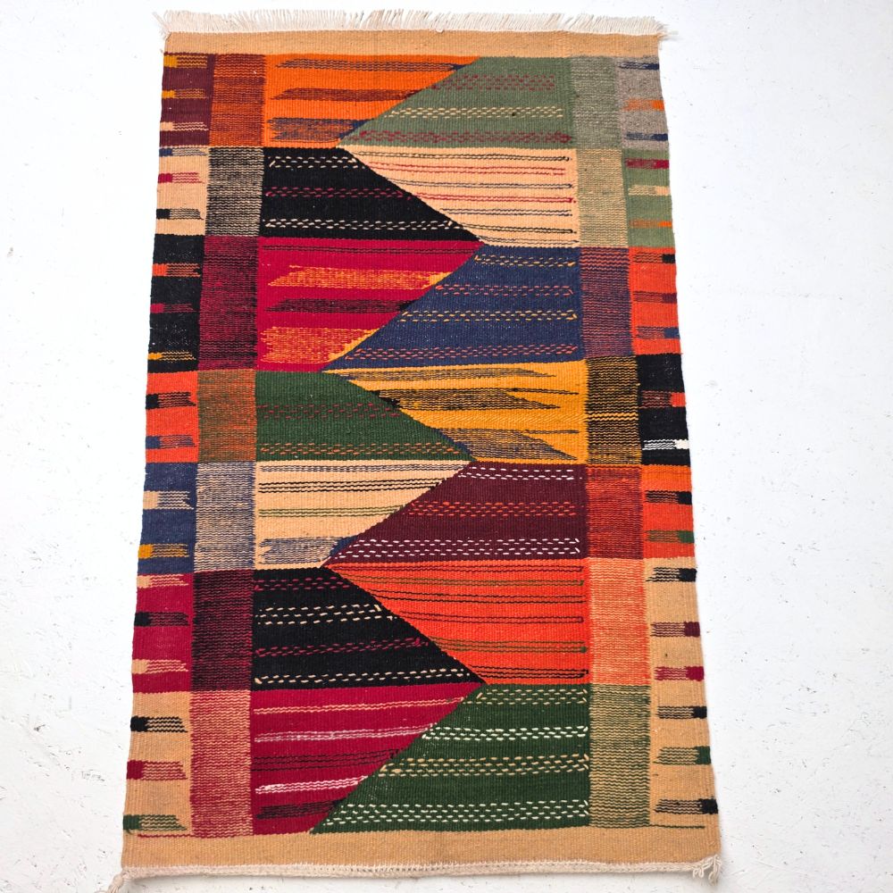 Bohemian Moroccan Azilal rug with bold geometric patterns in red, orange, purple, and multicolor wool, featuring abstract Berber tribal motifs and handwoven texture.