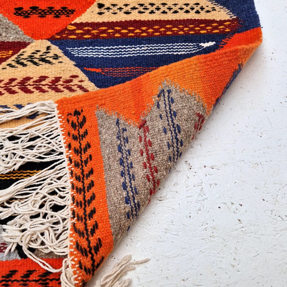 Colorful Moroccan Azilal rug with bold geometric patterns in red, orange, purple, and multicolor wool, featuring abstract Berber tribal motifs and handwoven texture.