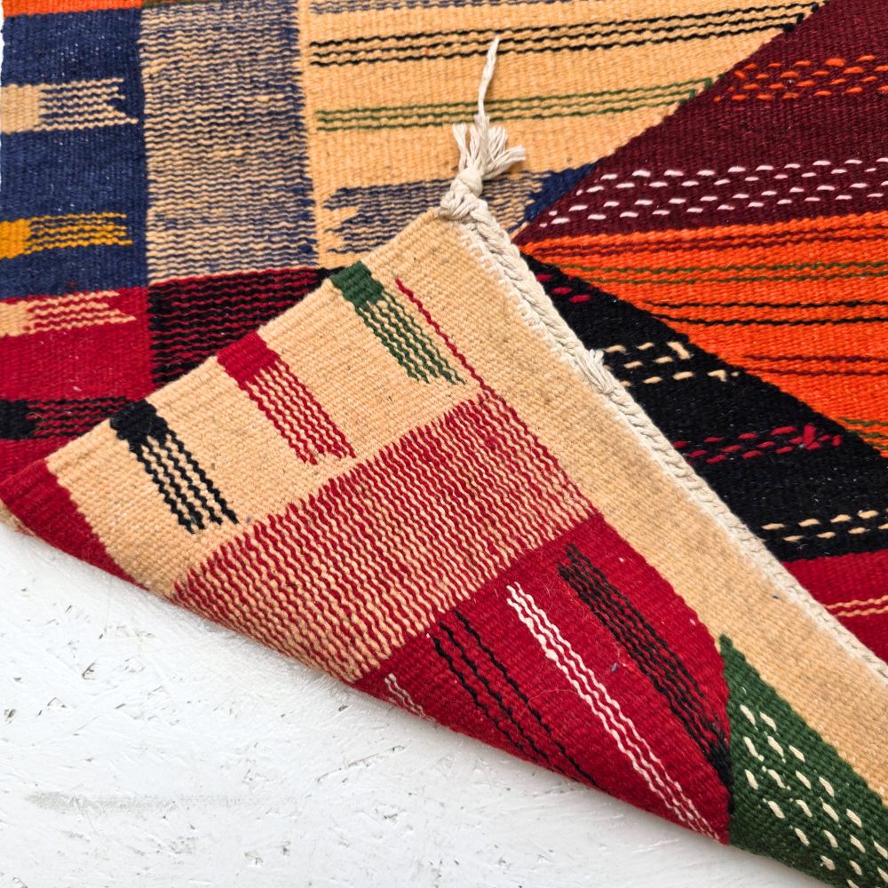 Bohemian Moroccan Azilal rug with bold geometric patterns in red, orange, purple, and multicolor wool, featuring abstract Berber tribal motifs and handwoven texture.