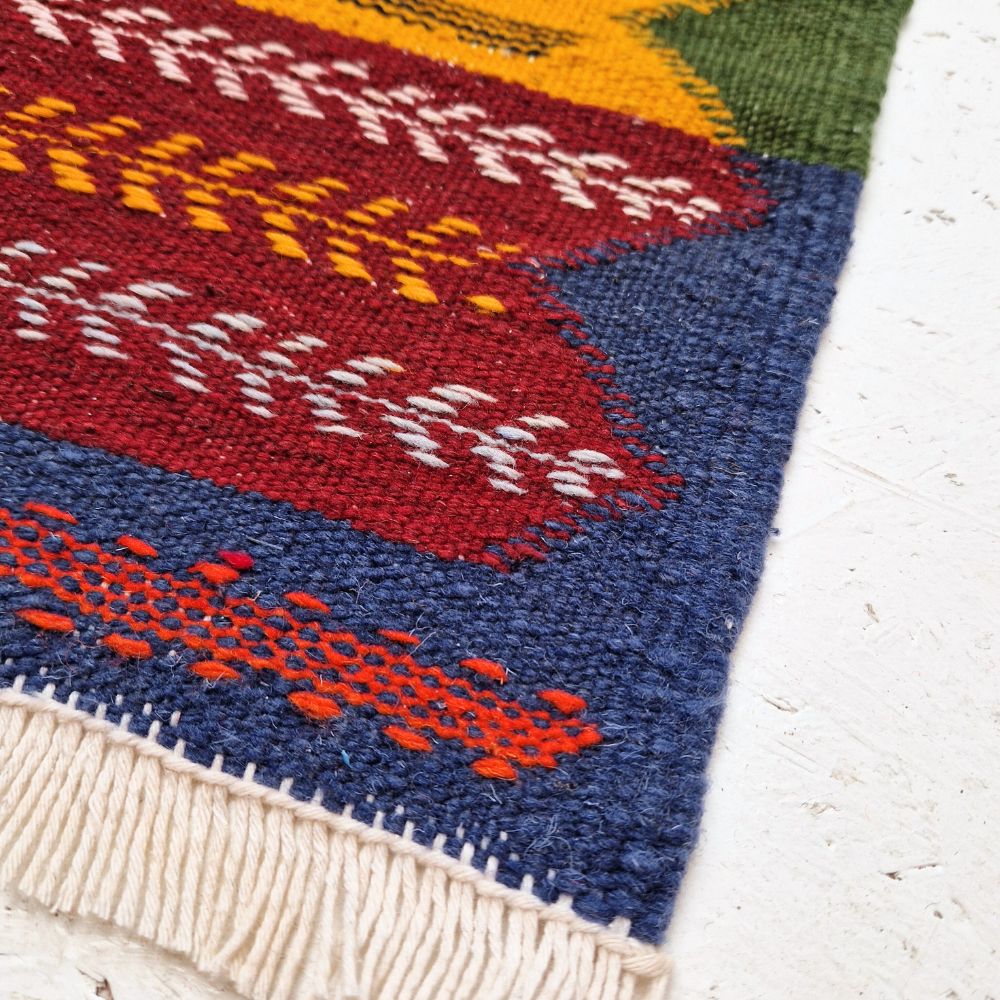 Colorful Moroccan Azilal rug with bold geometric patterns in red, orange, purple, and multicolor wool, featuring abstract Berber tribal motifs and handwoven texture.
