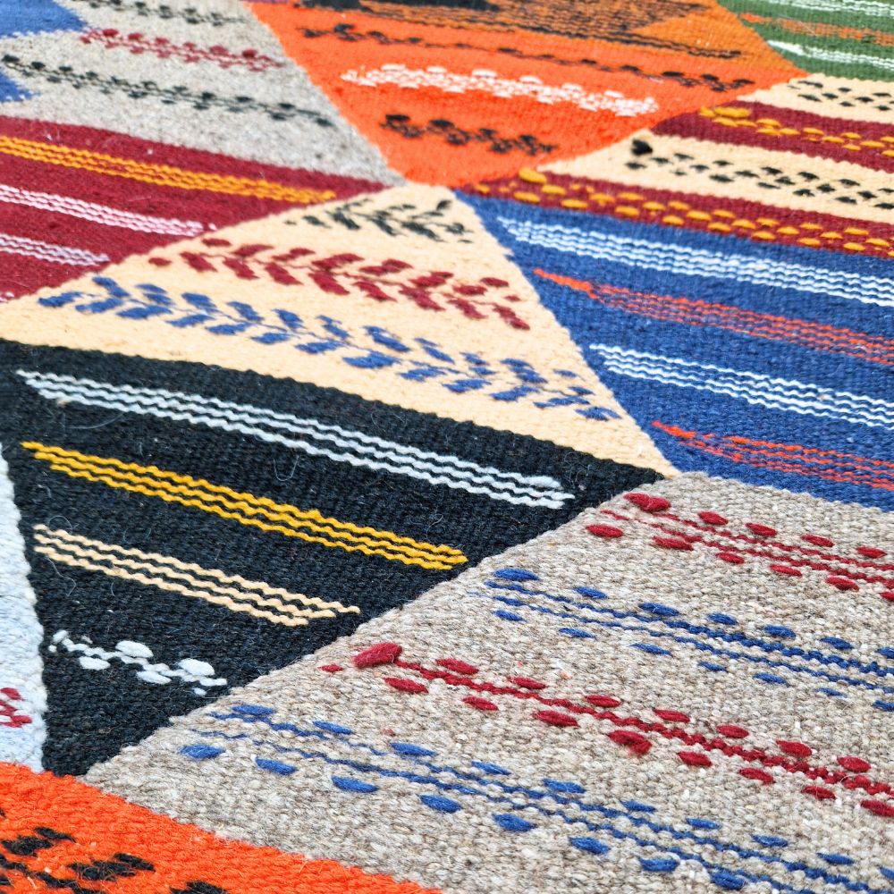 Colorful Moroccan Azilal rug with bold geometric patterns in red, orange, purple, and multicolor wool, featuring abstract Berber tribal motifs and handwoven texture.