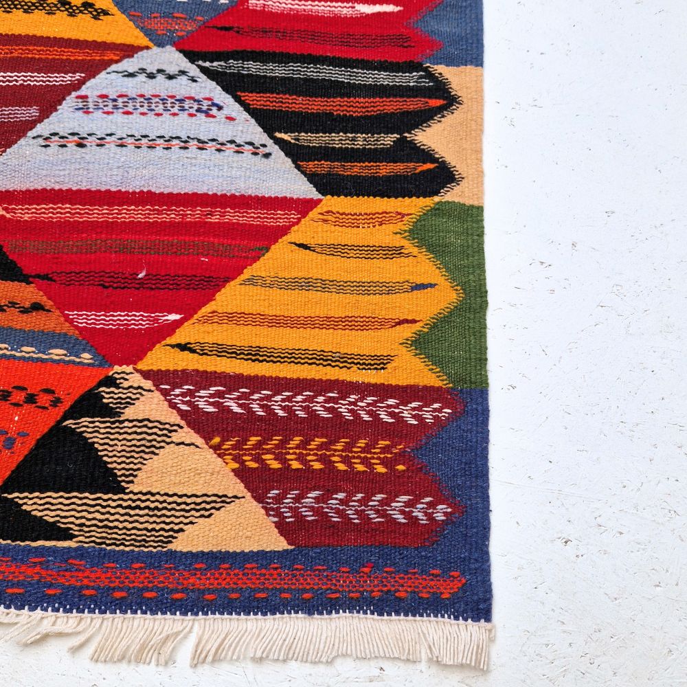 Colorful Moroccan Azilal rug with bold geometric patterns in red, orange, purple, and multicolor wool, featuring abstract Berber tribal motifs and handwoven texture.