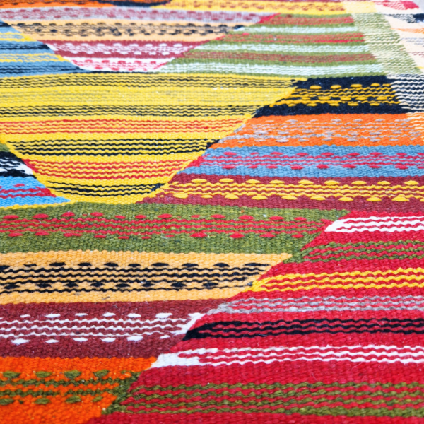 Bohemian Moroccan Azilal rug with bold geometric patterns in red, blue, white and multicolor wool, featuring abstract Berber tribal motifs and handwoven texture.