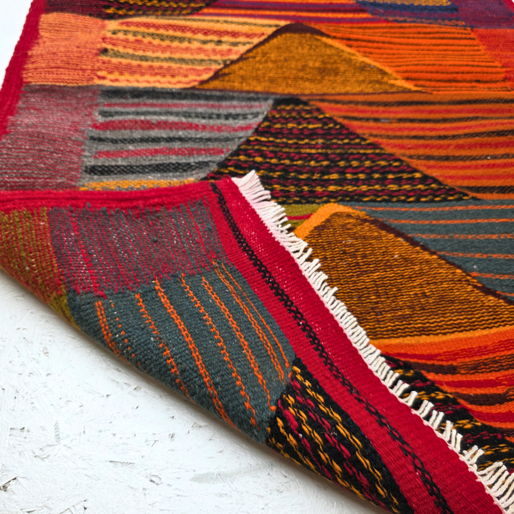 Bohemian Moroccan Azilal rug with bold geometric patterns in red, orange, purple, and multicolor wool, featuring abstract Berber tribal motifs and handwoven texture.