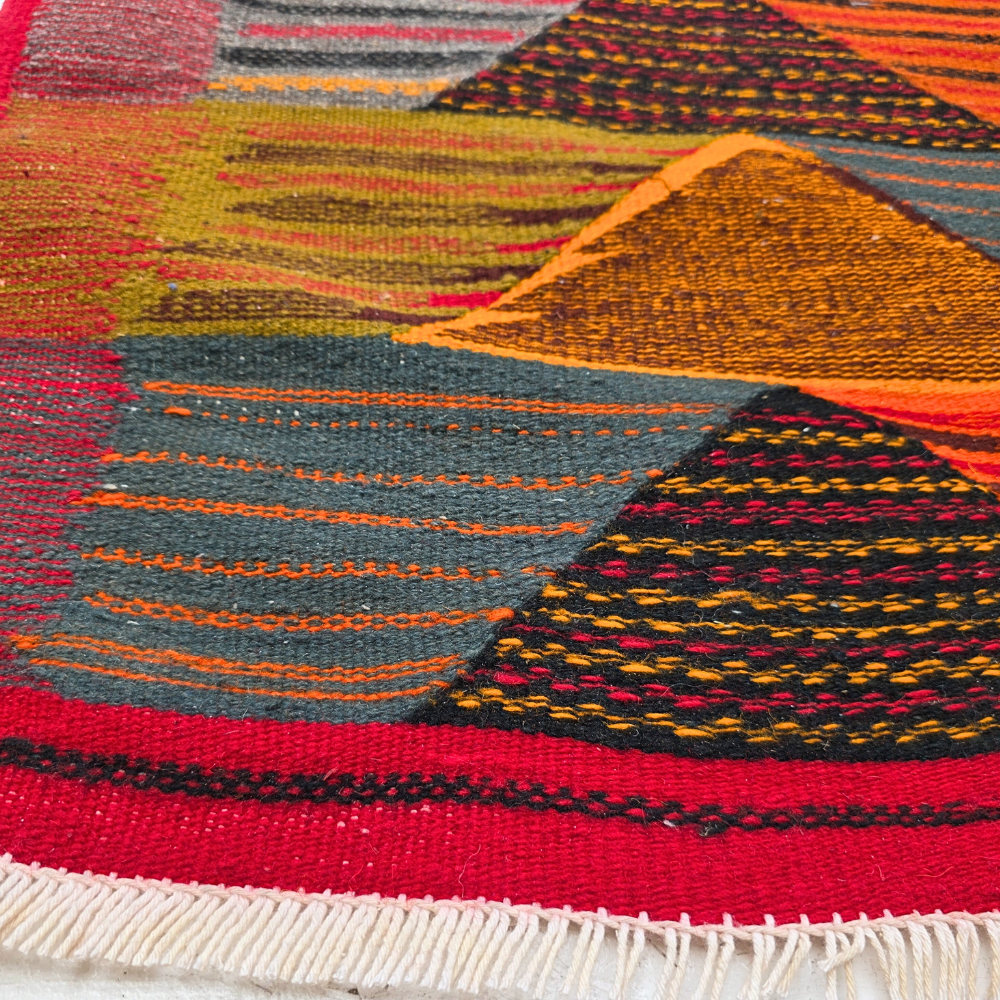 Bohemian Moroccan Azilal rug with bold geometric patterns in red, orange, purple, and multicolor wool, featuring abstract Berber tribal motifs and handwoven texture.