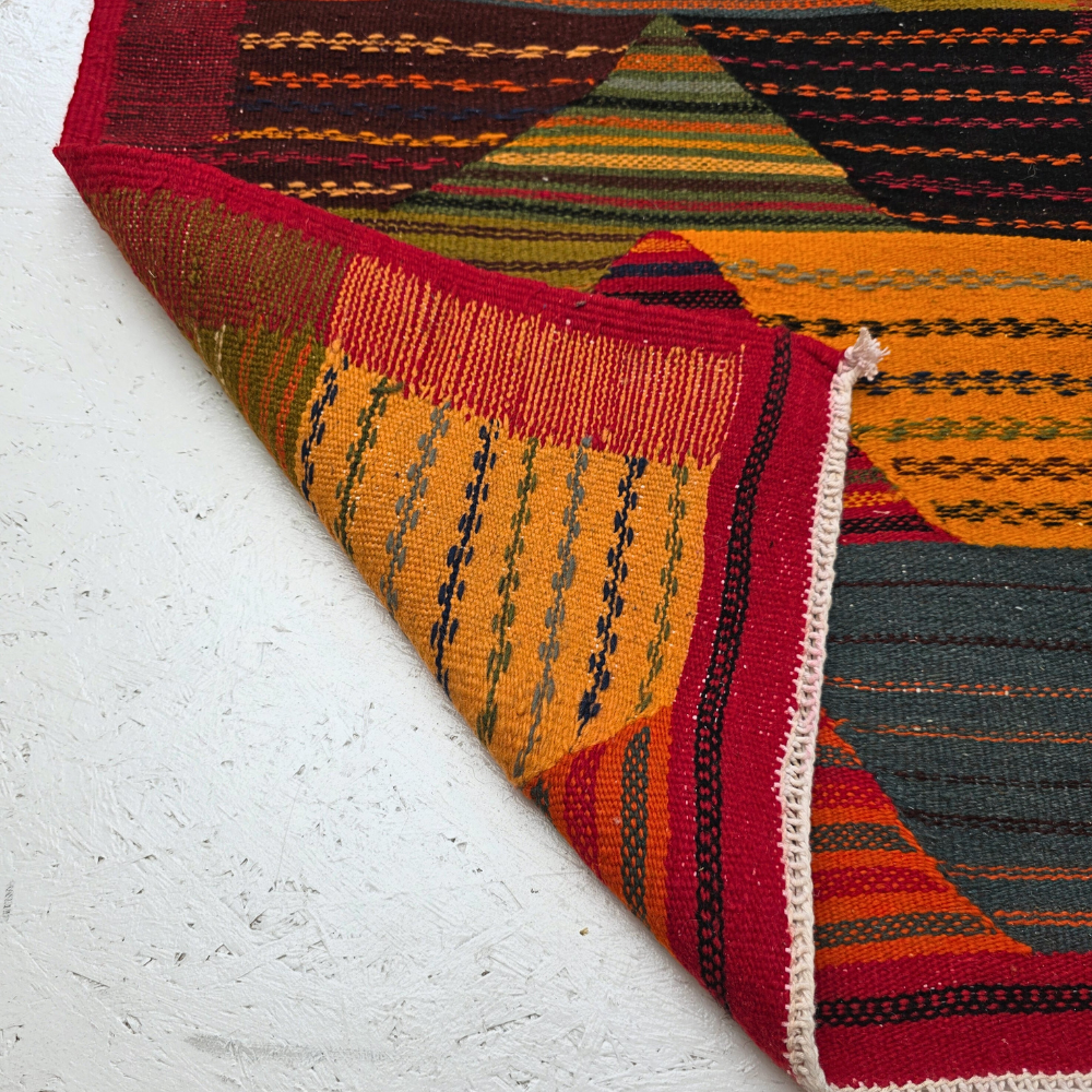 Bohemian Moroccan Azilal rug with bold geometric patterns in red, orange, purple, and multicolor wool, featuring abstract Berber tribal motifs and handwoven texture.