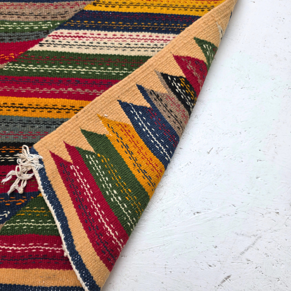 Bohemian Moroccan Azilal rug with bold geometric patterns in red, orange, purple, and multicolor wool, featuring abstract Berber tribal motifs and handwoven texture.