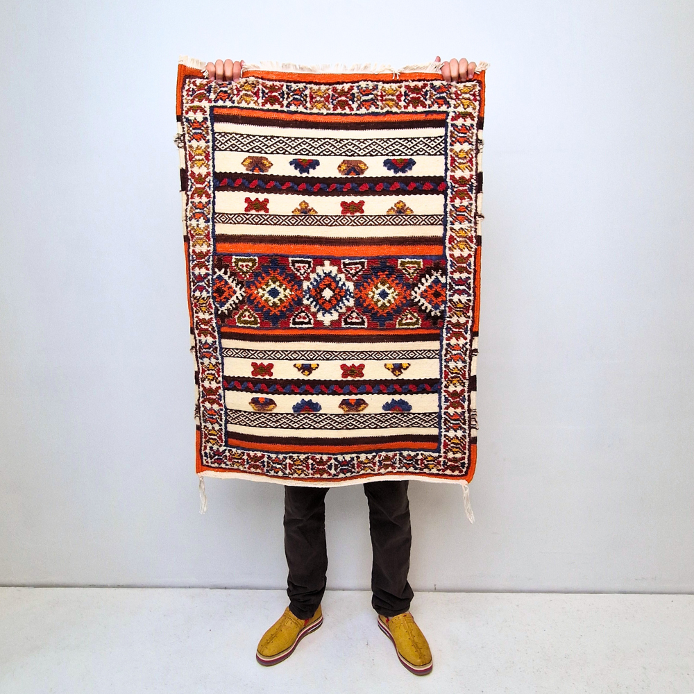 Bohemian Moroccan Azilal rug with bold geometric patterns in red, blue, white and multicolor wool, featuring abstract Berber tribal motifs and handwoven texture.